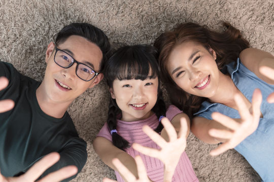 Relax Asian family laying with happy and smile on carpet in livi